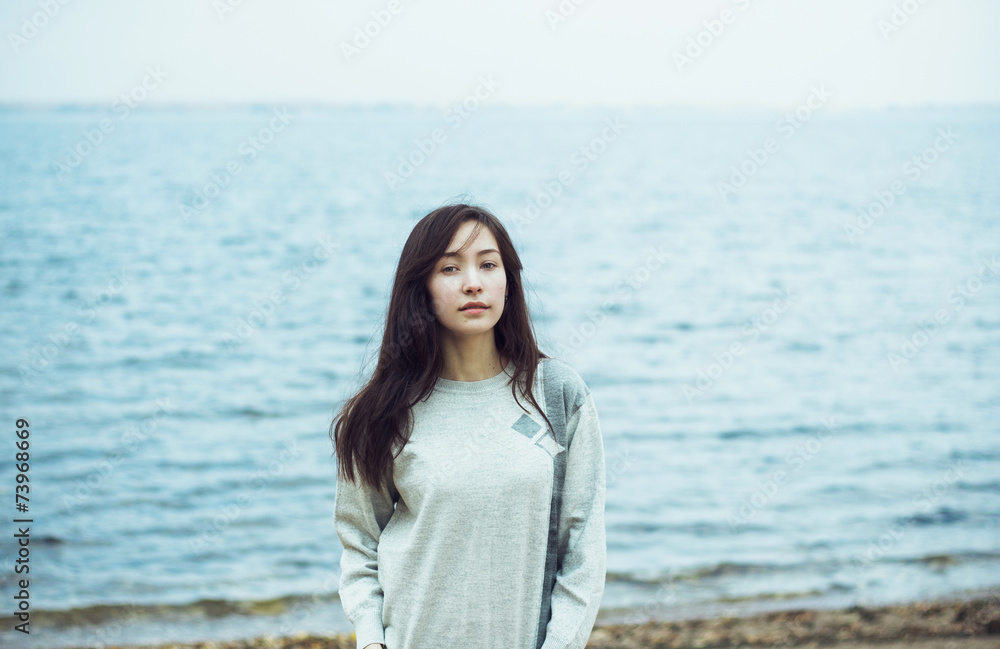 Young beautiful woman on cold sea background Young beautiful woman on cold sea background