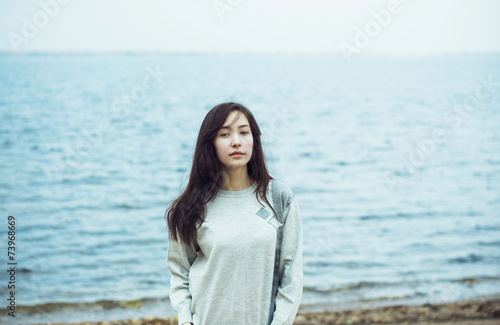 Young beautiful woman on cold sea background