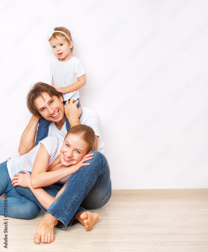 Happy family on  floor near  empty  wall in the apartment