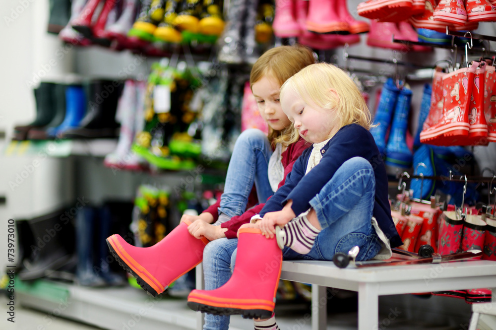 Two sisters choosing and trying on new rain boots Two sisters choosing and trying on new rain boots