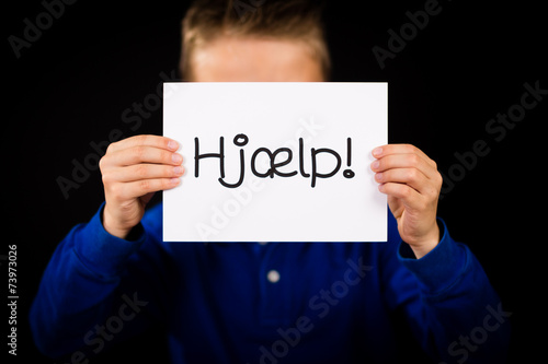 Child holding sign with Danish word Hjaelp - Help