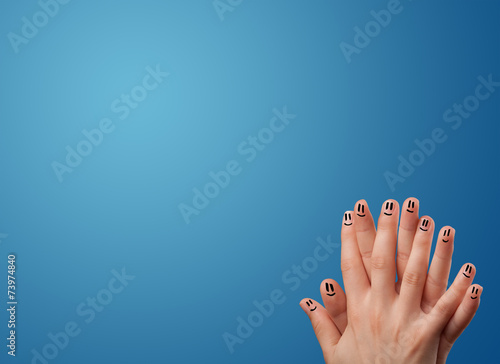 Happy smiley face fingers looking at empty blue background copy