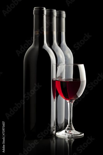 Elegant red wine glass and a wine bottles in black background