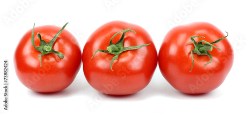 three fresh tomatoes with green leaves