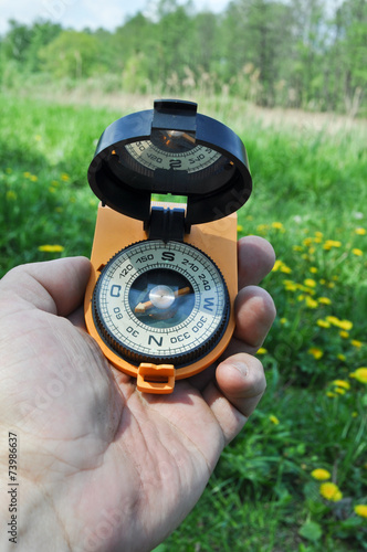 Compass in hand, against the background of blooming meadows.