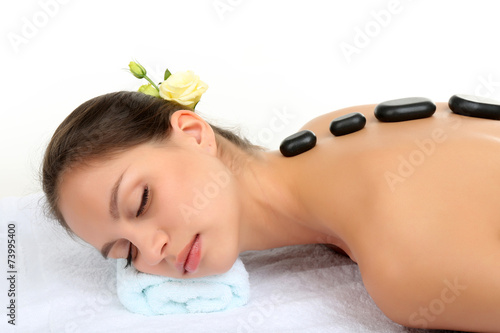 Beautiful young woman in spa salon with spa stones
