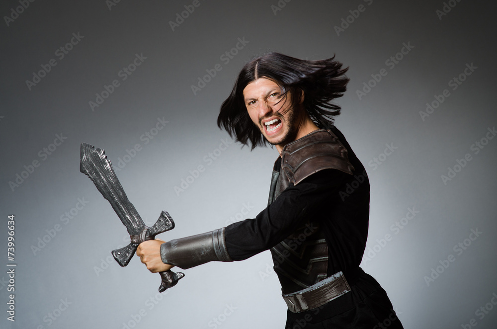 Angry knight with sword against dark background Angry knight with sword against dark background
