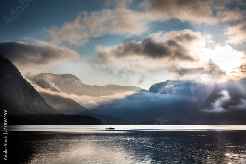 Small boat on foggy lake in the mountains