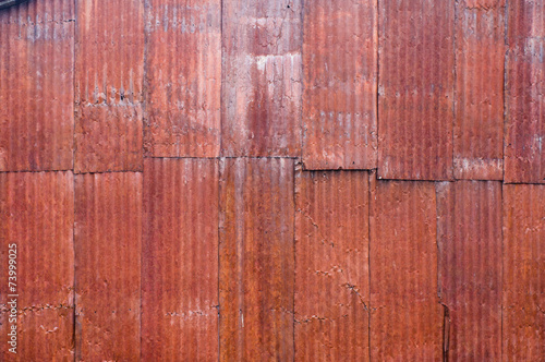 Red metal corrugated siding with rust
