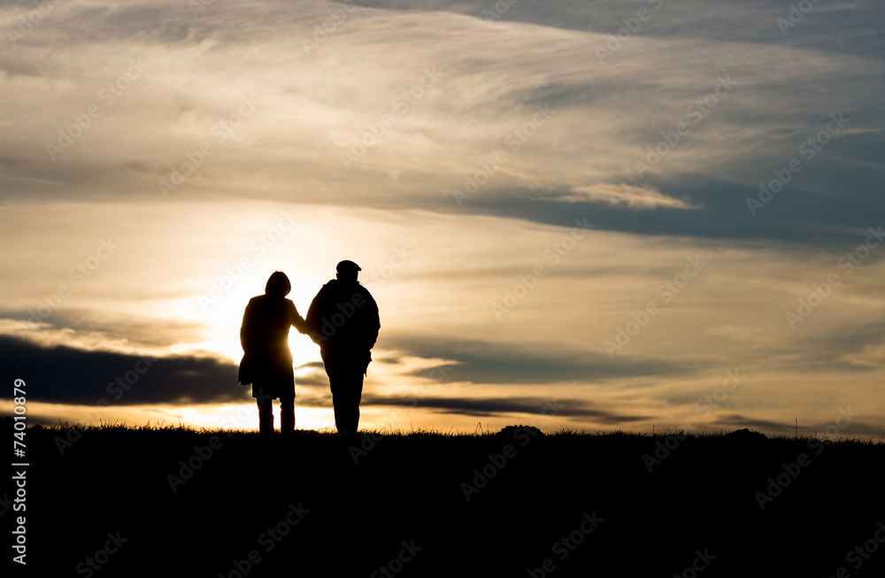 silhouette of elderly couple walking on hill