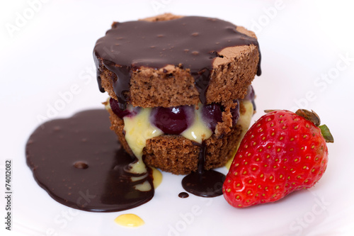 Chocolate cake on white plate with a strawberry