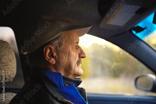 Old man with moustaches driving a car