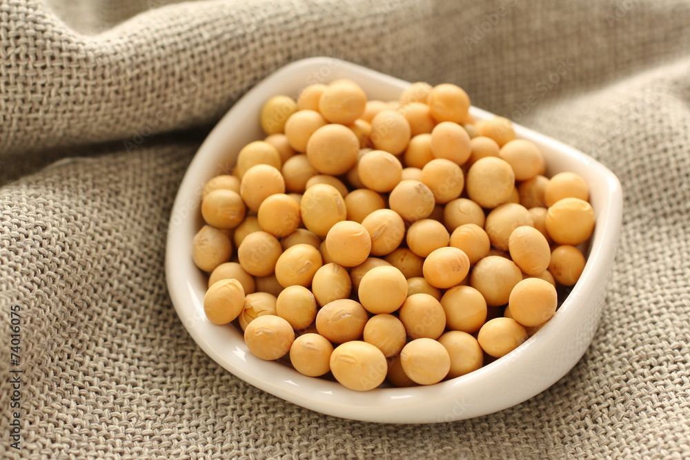 Soybeans in white ceramic bowl on sackcloth background Soybeans in white ceramic bowl on sackcloth background