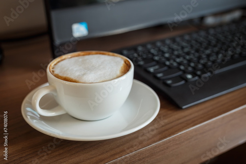 Coffee cup and computer on table
