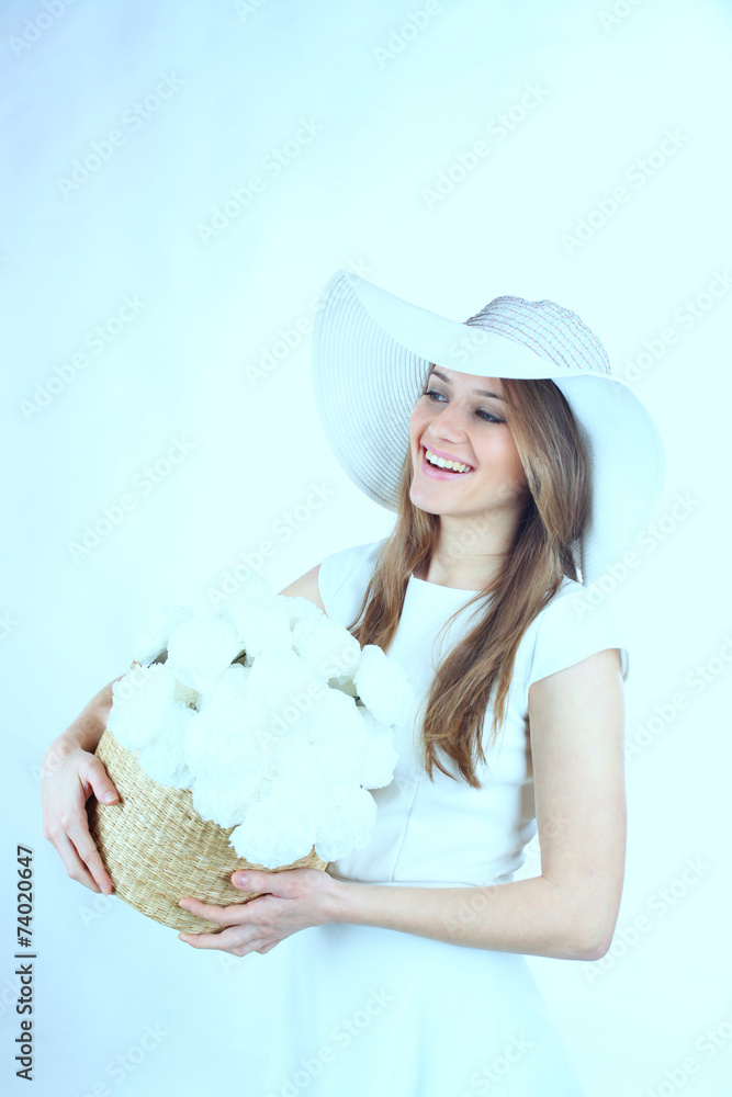 Beautiful young woman holding a basked of white flowers Beautiful young woman holding a basked of white flowers