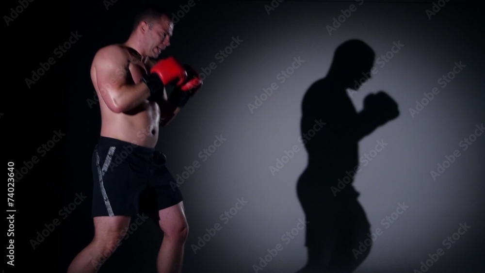 Boxer training shadow boxing over black background Boxer training shadow boxing over black background