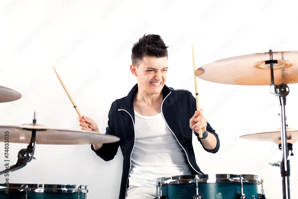 Fototapeta premium Expressive young drummer playing at the drums with drum stick