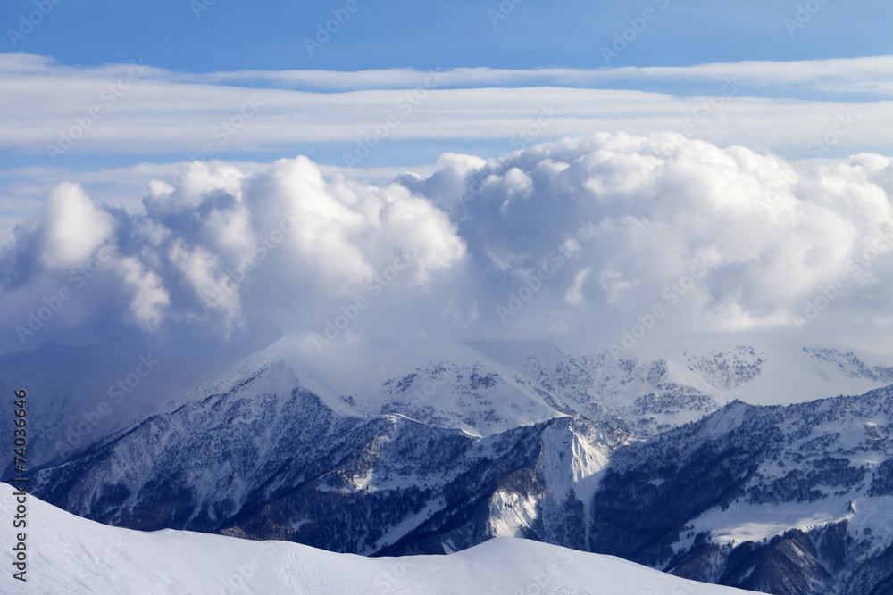 Snowy mountains in clouds and off-piste slope