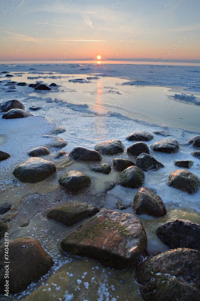 Stones in the sea froze in the ice at sunset Stones in the sea froze in the ice at sunset