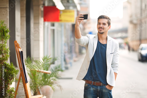 Young attractive man photographing on the street