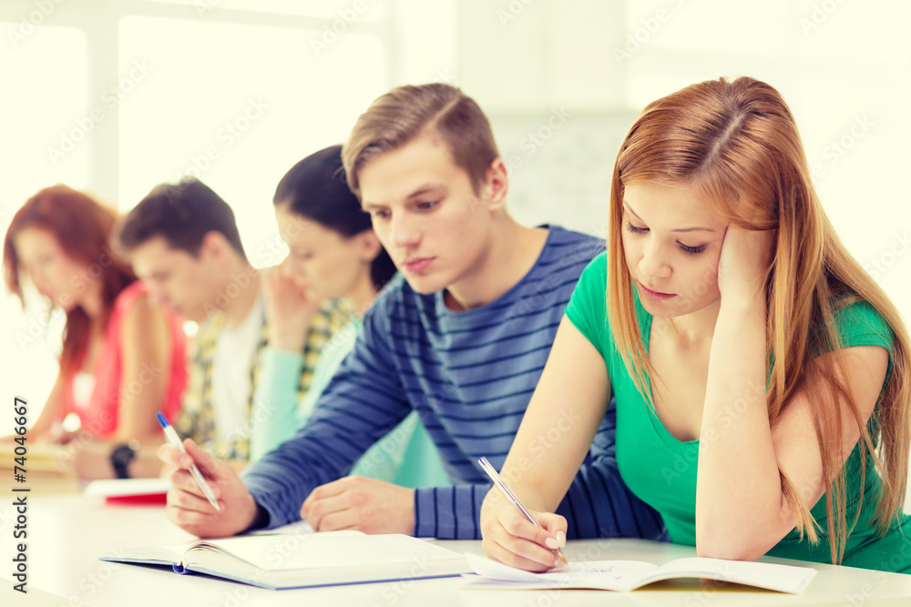 Fototapeta premium zmęczeni uczniowie z podręcznikami i książkami w szkole