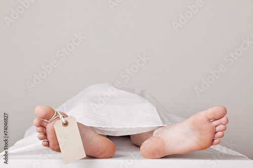 Covered dead body in the morgue with a tag attached to the toe
