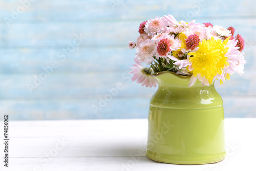 Fototapeta Naklejka Na Ścianę i Meble -  Beautiful flowers in pitcher on table on light blue background
