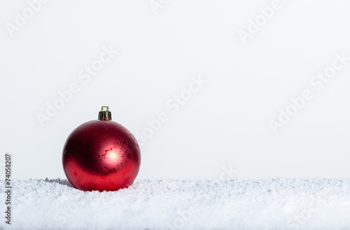 Single red Christmas ornament on snow