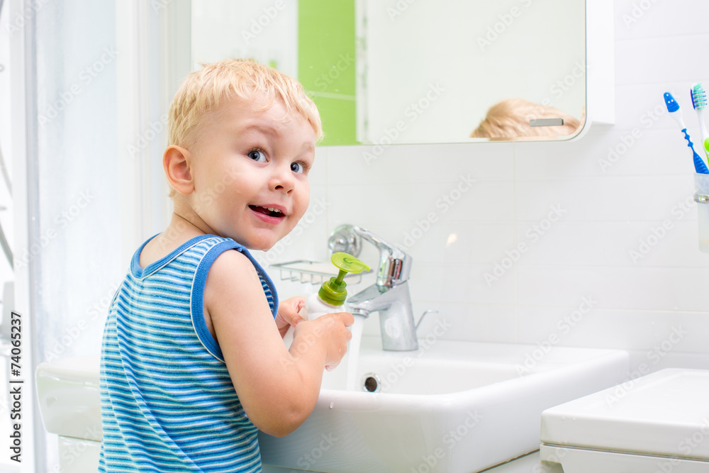 kid washing his face and hands in bathroom kid washing his face and hands in bathroom