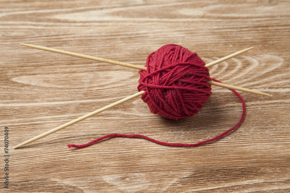 red ball of yarn with two knitting needles
