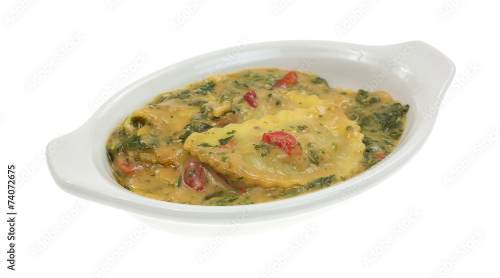 A baking dish with cooked ravioli in wine sauce with spinach A baking dish with cooked ravioli in wine sauce with spinach