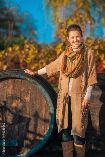 Full length portrait of happy young woman near wooden barrel 