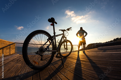 Fototapeta Naklejka Na Ścianę i Meble -  silhouette of sportsman and mountain bike at sunset
