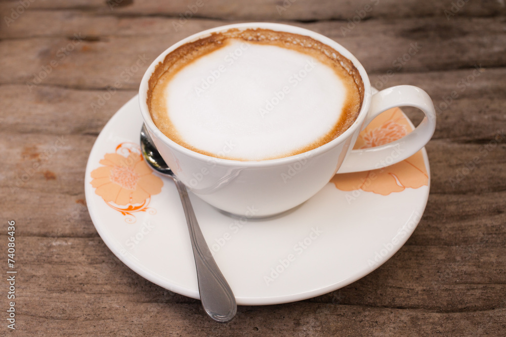 Cup of hot cappuccino coffee on wooden table.