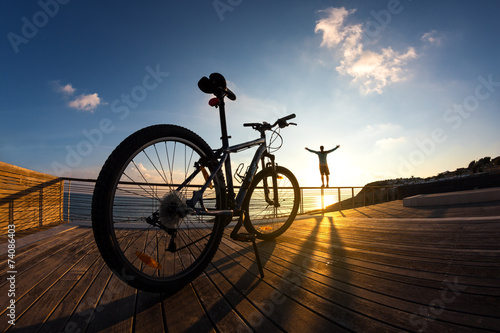 silhouette of sportsman and his mountain bike at the sunset