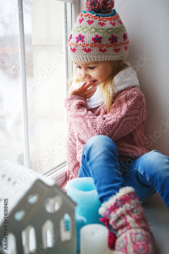 Little girl sitting on a window sill