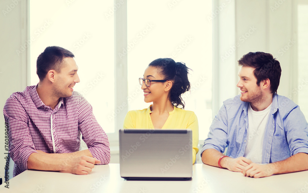 three smiling colleagues with laptop in office three smiling colleagues with laptop in office
