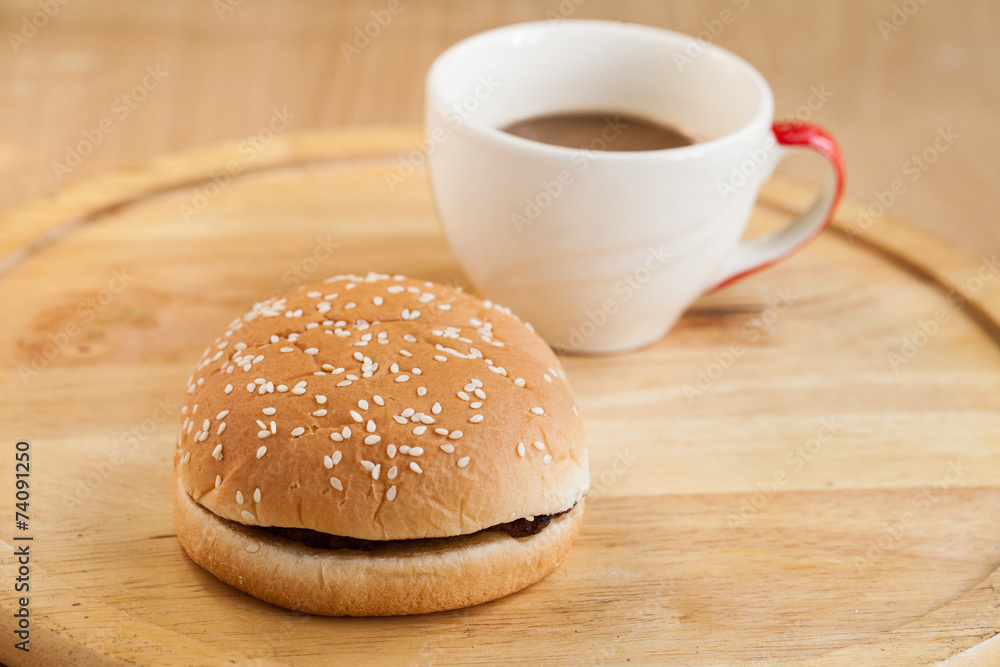 hamburgers and cup of black coffee on wooden board.