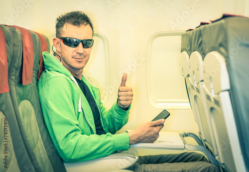Billede på lærred Hipster man passenger satisfied with thumbs up in airplane