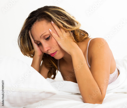 Sad woman lies in bed
