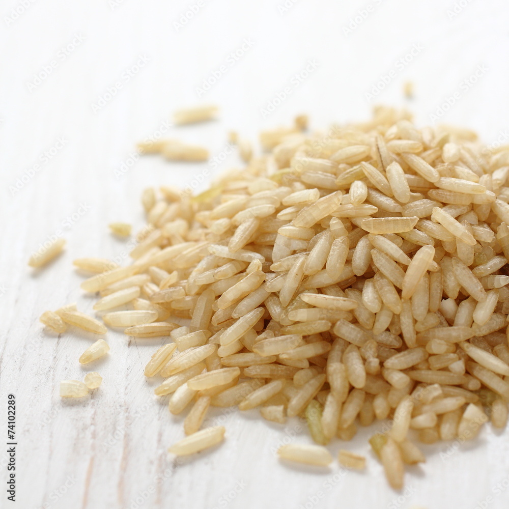 Pile of brown rice grain on white wooden background Pile of brown rice grain on white wooden background