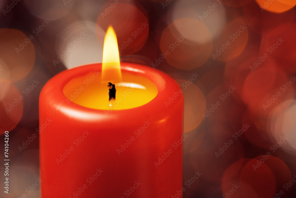 Macro of red candle with fire against defocused lights Macro of red candle with fire against defocused lights