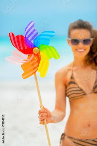 Closeup on smiling young woman showing colorful windmill toy 