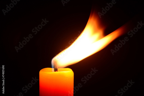 Orange candle burning on a black background