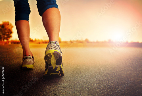 an athletic pair of legs on pavement during sunrise or sunset - healthy lifestyle 