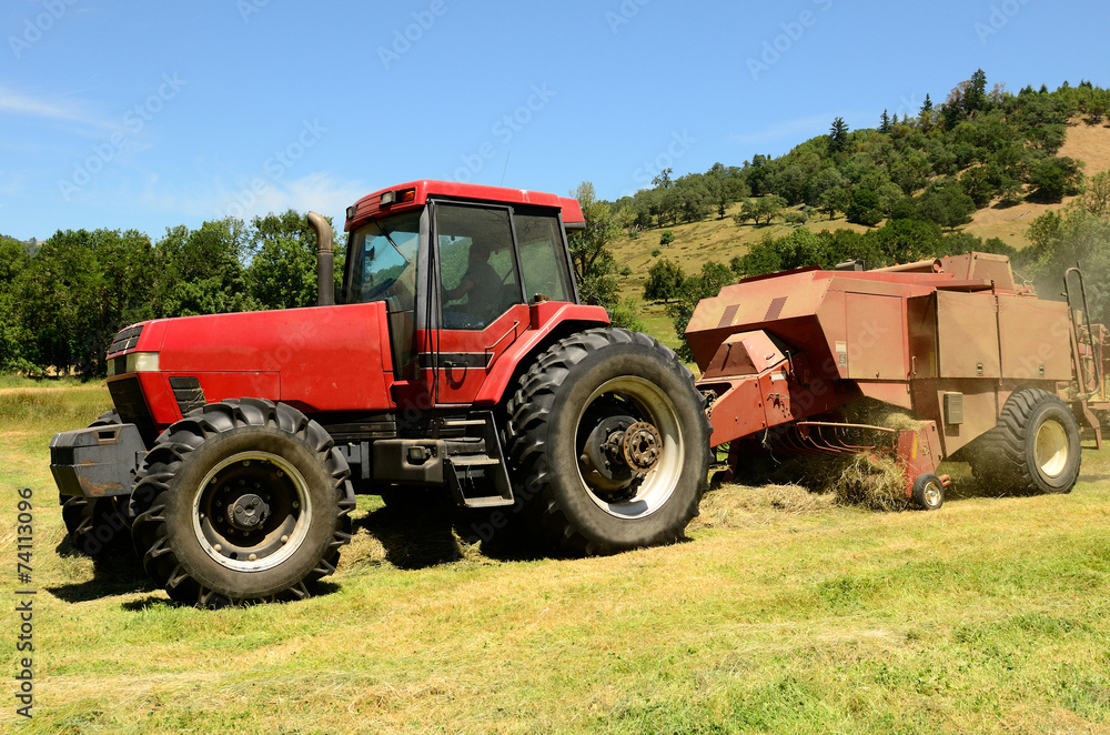 Large Baler working a small farm field of grass hay Large Baler working a small farm field of grass hay