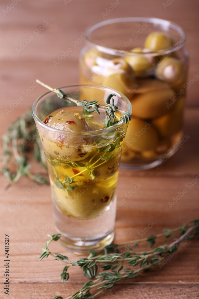 Green olives in oil with spices and rosemary in glass jars Green olives in oil with spices and rosemary in glass jars