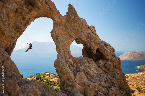 Rock climber hanging on rope while climbing cliff