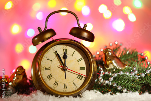 Alarm clock with Christmas decorations on bright background