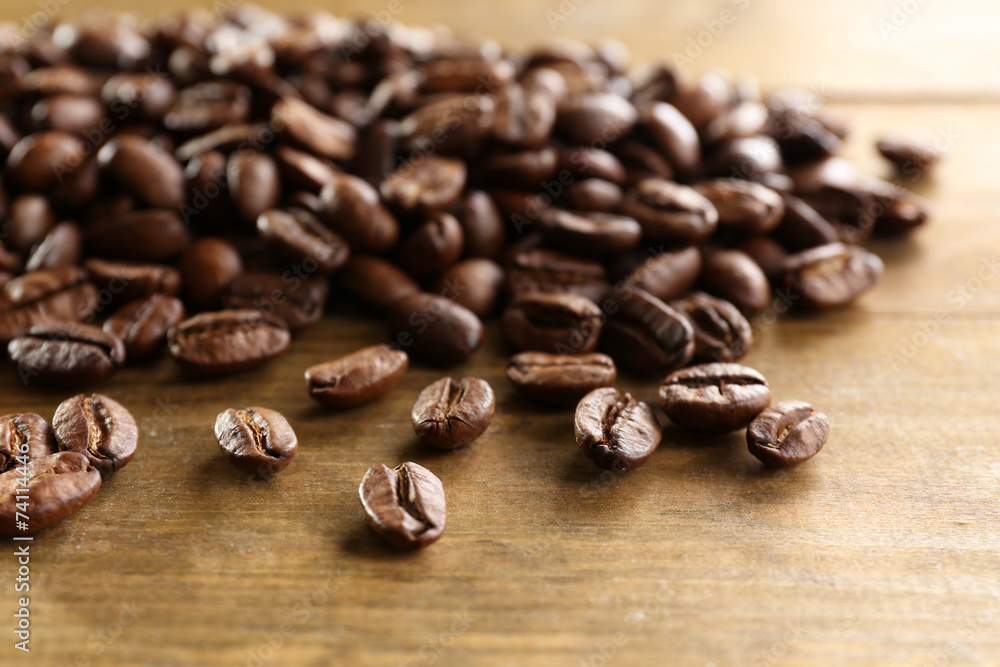 Naklejka premium Coffee beans on wooden background, close-up